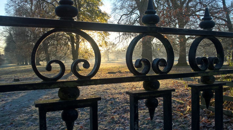 View through a wrought iron gate to Montacute House's frosty parkland.